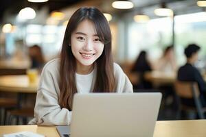 retrato de contento asiático hembra estudiante aprendizaje en línea en café comercio, joven mujer estudios con ordenador portátil en cafetería, haciendo deberes foto