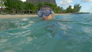 langzaam beweging visie van klein jongen zwemmen in de Indisch oceaan in de snorkelen masker en nemen een afbeelding, haven louis, Mauritius eiland video