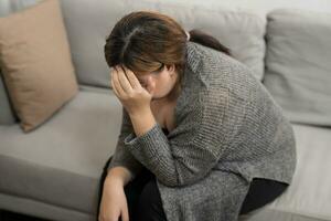 triste exceso de peso más Talla mujer pensando acerca de problemas en sofá trastornado niña sensación solitario y triste desde malo relación o Deprimido mujer trastorno mental salud. foto