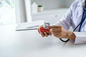 médico con anatómico modelo de humano corazón cardiólogo apoyos el corazón. corazón diagnosticar médico chequeo cardiólogo en examen habitación foto