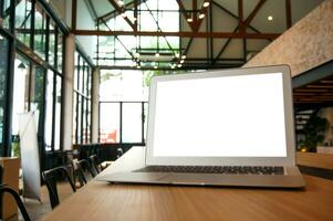 Laptop with Mock up blank screen on wooden table in front of cafe space for text. product display computer laptop montage- technology Freelance work concept photo