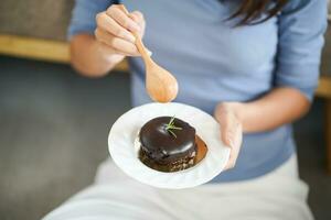 Beautiful Asian woman eating tasty chocolate cake. Teen girl eating the cake. photo