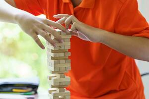 Asian father and son playing wood blocks game Carefree kid playing wood blocks game building constructor from blocks with father at home photo