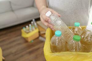 Home recycle eco green zero concept Man throwing empty plastic bottle in recycling bin with yellow garbage bags at home photo