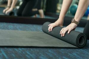 Fitness woman folding exercise mat before working out in yoga studio. rolling Yoga mat  after training healthy lifestyle photo