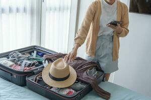 Asian girl preparing vacation in bedroom. Woman doing checklist before holidays trip photo