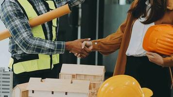 costruzione e struttura concetto di ingegnere o architetto incontro per progetto Lavorando con compagno e ingegneria utensili su modello edificio e planimetria nel Lavorando luogo, contrarre per tutti e due aziende. video