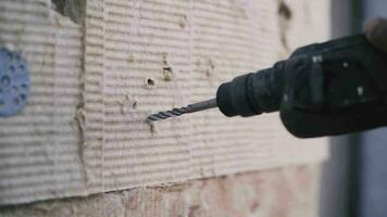 trabajador simulacros un pared con un eléctrico perforar video