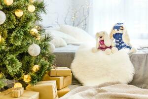 Handmade knitted rabbit. Christmas Bunny in a scarf and hat with a large pumpon among the decorative Christmas trees and balls. Christmas composition photo