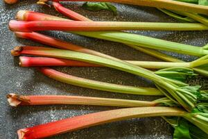 Fresh ripe green and red rhubarbs on a rustic grey table photo