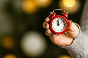 Attractive dreaming woman holding clock near christmas tree. photo