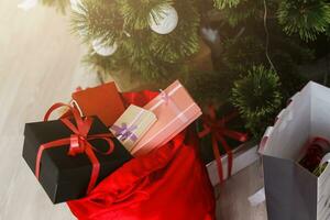 Gifts in bag lie near a decorated Christmas or New Year tree. red bags of Cristmas presents photo