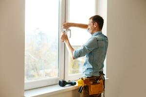 Man worker mounting window on balcony. photo