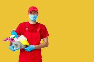 Cleaning man with a bucket and cleaning products on color background. photo