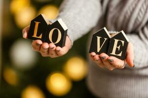 mujer sostiene letras amor cerca Navidad árbol con juguetes foto