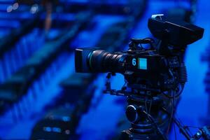 Professional camcorder, video camera, black silhouette of camera on blue background, close up photo