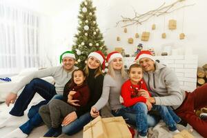 Closeup portrait of big happy family with Santa Claus lying down near Christmas tree, holiday celebration, joy and happiness concept photo