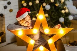 Portrait of happy woman in santa hat holding big golden star. photo