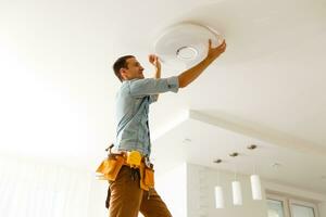 Electrician is installing and connecting a lamp to a ceiling. photo