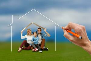 Portrait of happy family on the meadow under a dream home photo