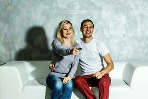 Young man watching football with his wife at home photo