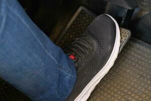 A foot stepping on the brake ready to start an automatic car. Close up right foot with black shoe step on the car brake to reduce speed. A man pressing brake pedal by foot to slow down the car. photo