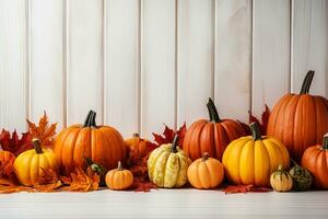 Various ripe orange pumpkins lie in maple leaves on a white wooden surface. Thanksgiving Day, Halloween background photo