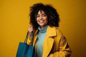 Charming smiling curly african american woman in a yellow coat with a blue shopping bag photo