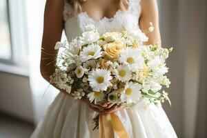 closeup of a delicate wedding bouquet with daisies in the hands of the bride near the window photo