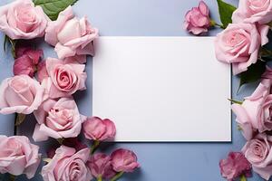 mockup white blank paper sheet with pink roses flowers top view on blue background, floral template empty card flat lay for design with copy space photo
