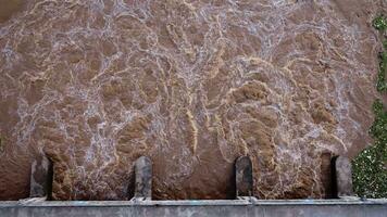 antenne visie van water vrijgelaten van de afvoer kanaal van de beton dam is een manier van overlopend water in de regenachtig seizoen. top visie van troebel bruin Woud water stromen van een dam in Thailand. video