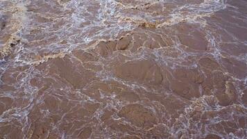 vue aérienne de l'eau libérée du canal de drainage du barrage en béton est un moyen de déborder de l'eau pendant la saison des pluies. vue de dessus de l'eau de la forêt brune trouble s'écoule d'un barrage en thaïlande. video