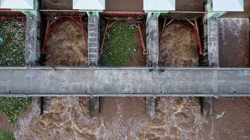 vue aérienne de l'eau libérée du canal de drainage du barrage en béton est un moyen de déborder de l'eau pendant la saison des pluies. vue de dessus de l'eau de la forêt brune trouble s'écoule d'un barrage en thaïlande. video