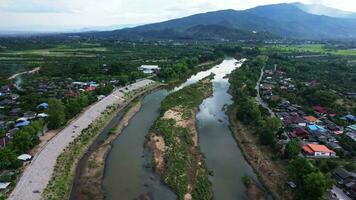 antenn se av de ping flod tvärs över ris fält och lantlig byar under solnedgång. visningar av chiang mai byar och de ping flod från en Drönare. video