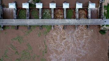 Aerial view of water released from the drainage channel of the concrete dam is a way of overflowing water in the rainy season. Top view of turbid brown forest water flows from a dam in Thailand. video