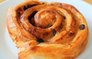 Close up beside view of raisin bread or Pain aux raisin on white plate. photo