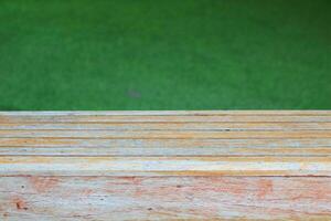 Old and pale of brown wood plank with some slip off color and green artificial grass background. photo