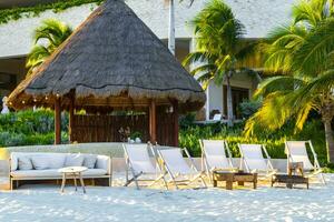 Palapa thatched roofs palms parasols sun loungers beach resort Mexico. photo