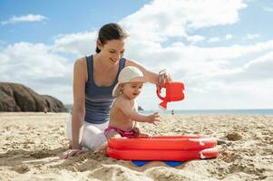 Mother playing with little daughter on the beach photo