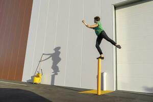 Acrobat standing on pole, casting shadow at cleaning bucket photo