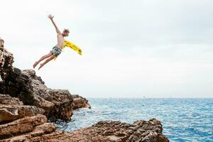 Man with airbed jumping from rock into the sea photo