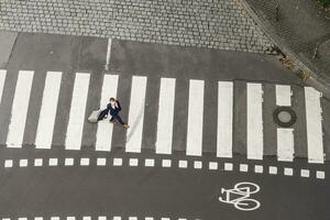 Germany, businesswoman with rolling suitcase walking on zebra crossing, view from above photo