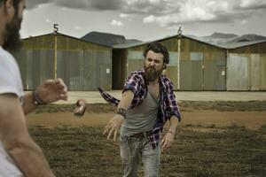 Man with full beard throwing beverage can to opponent photo