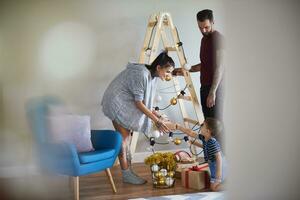 Modern family at home at Christmas time using ladder as Christmas tree photo