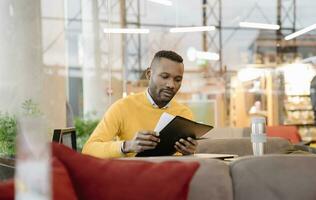 Man with reusable cup reading documents in a cafe photo