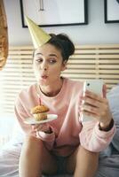 mujer soplo fuera el vela en el cumpleaños pastel y haciendo un selfie foto