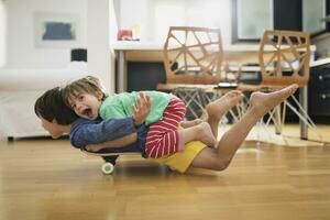 Two brothers at home lying on skateboard together having fun photo