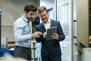 Smiling businessmen using digital tablet at industry photo