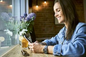 Smiling young woman using phone in cafe photo