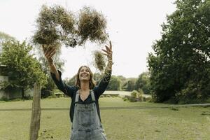 Happy young woman in the countryside throwing up hay photo